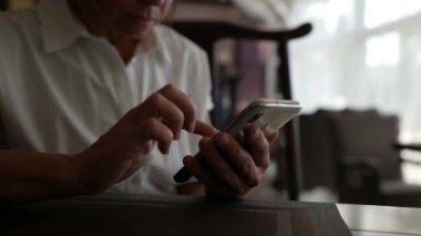 Evde akıllı telefon kullanan bir kızın eli bir mesaj yazmaktadır. Yetişkin bir kadının elinin yakın çekimi.