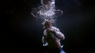 Bir karma dövüş sanatları dövüşçüsü havuzda su altında yumruk pratiği yapıyor.