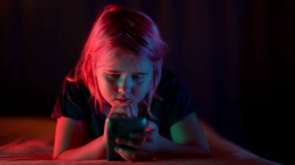 Küçük kız gece vakti akıllı telefondan video izliyor. Yatak odasında, internet bağımlılığı. — Stok video