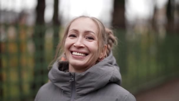 가을에 길을 걷고 있는 우스꽝 스러운 머리 스타일의 행복 한 중년 여성의 사진 — 비디오