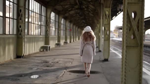 Pełna wdzięku urocza kobieta chodzi samotnie po terminalu starego dworca kolejowego w zimowy dzień — Wideo stockowe
