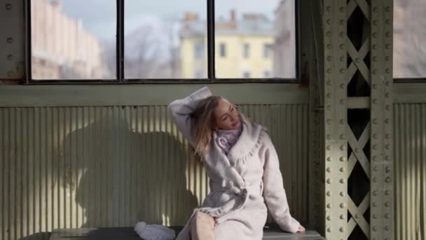 Seductora mujer adulta en la vieja estación, sentada en el banco y tocando su cabello largo — Vídeos de Stock