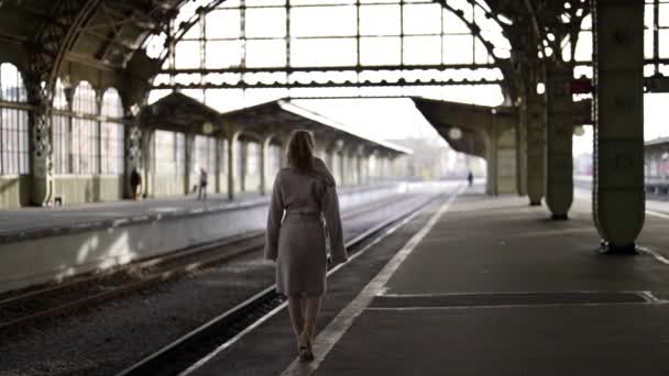Winterochtend in oud station, eenzame vrouw loopt op perron, achteraanzicht — Stockvideo