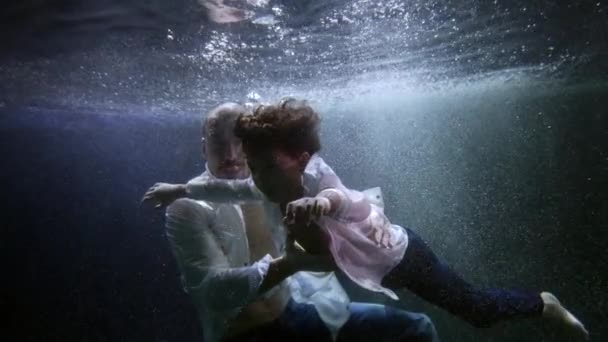 Отец и его маленький сын под водой, плавают и ныряют под поверхностью темного бассейна — стоковое видео