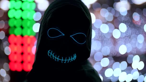 Close-up of a creepy portrait of death in the dark against the background of neon holiday lights — Stock Video