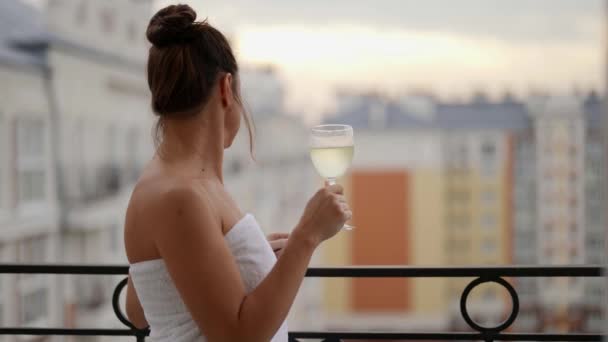 Mulher relaxada em toalha de banho está admirando paisagem urbana e beber vinho branco sozinho, relaxante no fim de semana — Vídeo de Stock