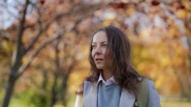 Güzel, orta yaşlı bir kadın güzel bir sonbahar gününde parkta tek başına yürüyor.