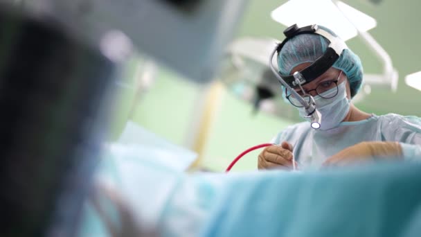 Concentrated surgeon is working in operating room, woman is wearing sterile clothes and gloves — 图库视频影像