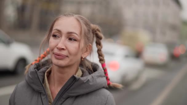 Mooie middelbare leeftijd dorpsvrouw met grappige kapsel van vlechten staat op straat en glimlachen — Stockvideo