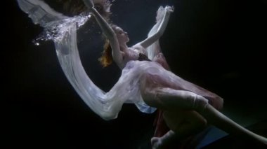 Suyun altında balerin, ipek elbiseli zarif genç bayan suyun altında yüzüyor.