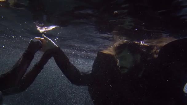 Підводний знімок чоловіка і жінки, що плаває в морі або річковій воді вночі, романтичний — стокове відео