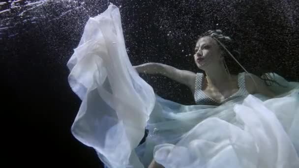 Onderwater slow motion shot van drijvende vrouw in donkere rivier — Stockvideo