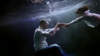 Baba oğluna suyun altında yüzmeyi öğretiyor. Yetişkin bir adam ve küçük bir çocuğun sualtı görüntüsü.