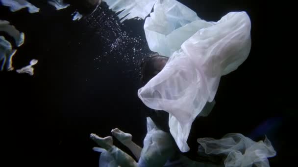Изящная и элегантная женщина плавает в темной глубине моря — стоковое видео