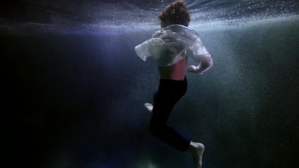 Little boy is floundering underwater, floating inside water of swimming pool, underwater shot — Stockvideo