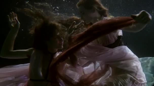 Dos hadas mujeres están flotando juntos bajo el agua, lesbianas amantes están nadando dentro de la piscina — Vídeo de stock