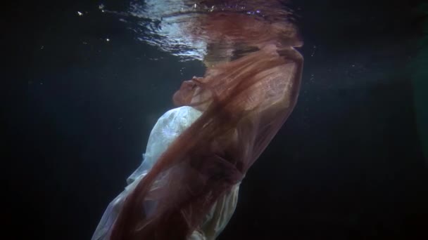 Mulher ruiva deslumbrante está flutuando debaixo d 'água, romântico e misterioso tiro em câmera lenta — Vídeo de Stock