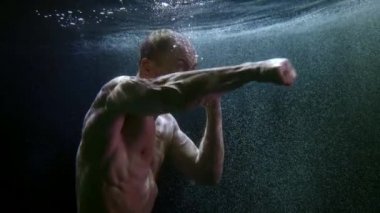Çıplak, kaslı, yumruklarını sallayan saldırgan adamın sualtı çekimi.
