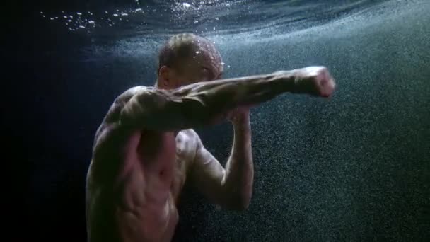 Podvodní záběr agresivního muže s nahou svalnatou hrudí mávající pěstmi — Stock video