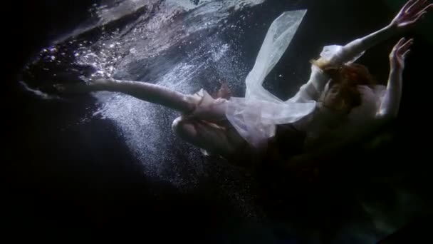 İpek elbiseli güzel bir kadın yüzüyor ve suyun altında takla atıyor. — Stok video