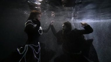 Denizin veya okyanusun derinliklerinde yüzen iki aşığın gizemli sualtı çekimi. Ortaçağ karakterleri.