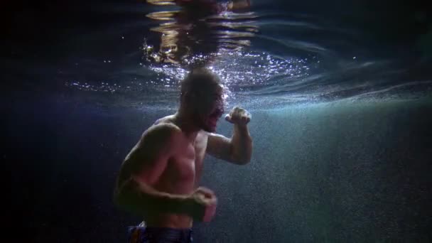 Underwater shot of man boxing inside swimming pool, holding breath and fighting — Vídeo de Stock