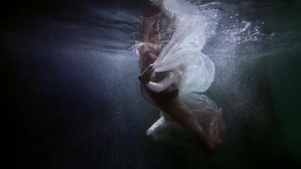 Verträumte Unterwasseraufnahme mit einer grazilen Frau, die unter der Wasseroberfläche im See oder Pool schwimmt — Stockvideo