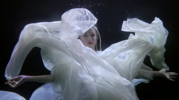 흰옷을 입고 느린 동작, 떠다니는 비단 직물로 낭만적 인 물 속에서 찍은 아름다운 여인 — 비디오