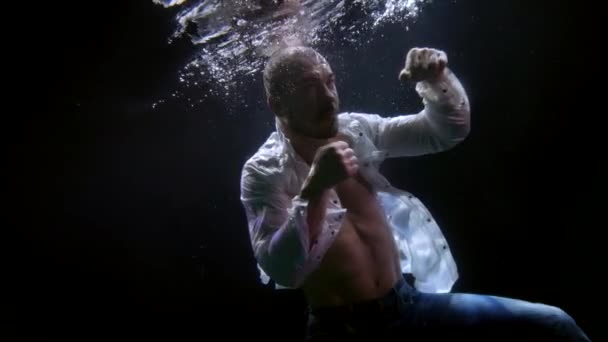 Agresszív harcos a víz alatt, elképesztő lövés lentről, férfi alak sötét mélységben — Stock videók