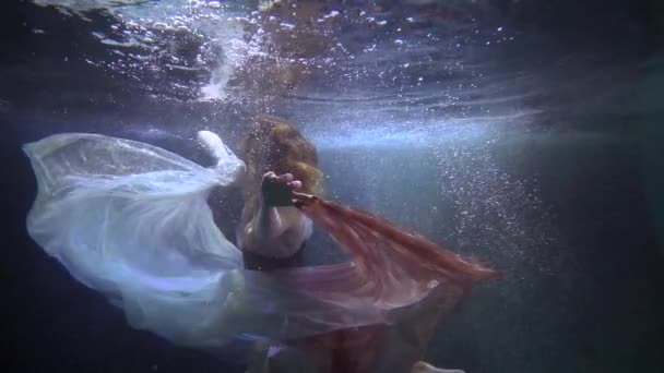 Μυστήριο και μαγεία υποβρύχια, χαριτωμένη γυναίκα κολυμπά αργά, παίζει με μεταξωτό φόρεμα — Αρχείο Βίντεο