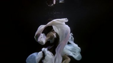 Suyun altında kadın figürü, örgülü ya da rastalı saç stili olan genç bir kadın derinlerde yüzüyor.