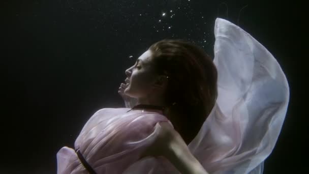 Romantic ballerina is floating gracefully underwater, medium portrait in dark water — Video Stock