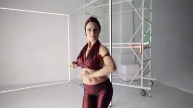 Baştan çıkarıcı bayan stüdyoda modern dans ediyor, vücudunu ve ellerini sallıyor.