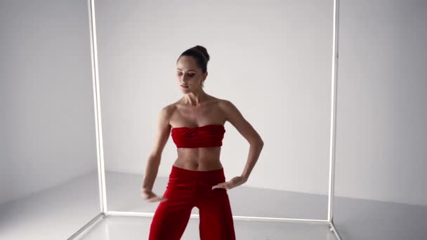 Brunette woman in red suit is dancing sexually in studio, oriental dance performance — Stockvideo