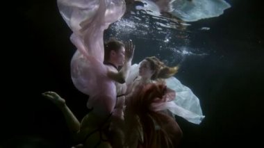 Havuzda yüzen lezbiyen kızların zarif dansları, deniz kızı masallarındaki gibi soyut sualtı çekimleri.