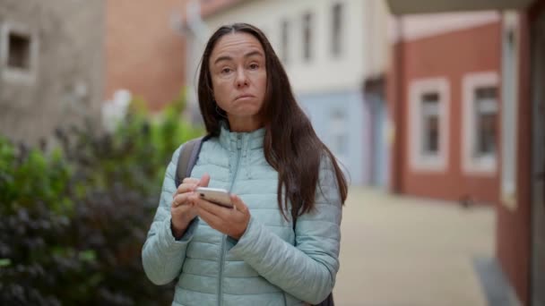 Portrait of an adult female tourist looking puzzled at the phone screen on a trip — Vídeo de Stock