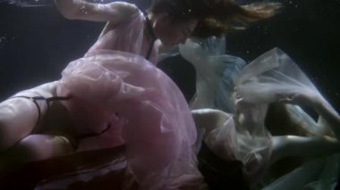 Suyun altında elbiseler içindeki zarif homoseksüel çift karanlık bir geçmişin derinliklerinde aşıklar. Etraflarında kabarcıklar uçuşuyor, birbirlerine tutkuyla bakıyorlar..