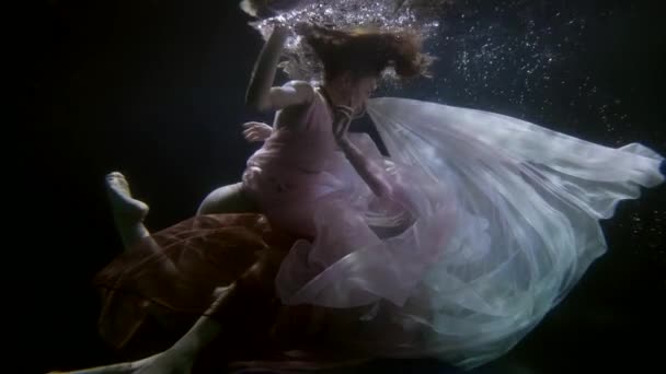 Joven gay mujer vestida en un vestido, nadando con su amante bajo el agua, pareja abrazando — Vídeos de Stock