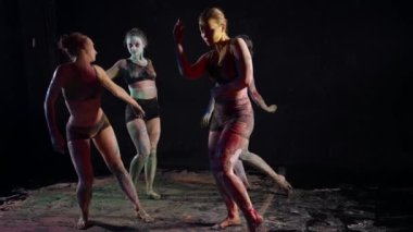 beautiful women dancers are stained with paints and dancing in dark room