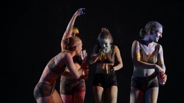 Cuatro mujeres divertidas están aplicando pinturas en la piel del otro, diversión y broma — Vídeo de stock