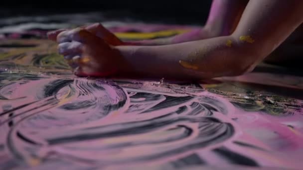 Pink and yellow paints on floor, woman is smearing dyes, closeup of hands — Stock Video
