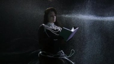 elegant brunette lady is reading old book underwater, subaquatic shot, magic and fairytale