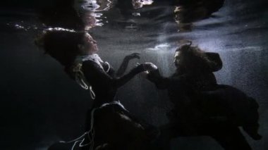 medieval sorcerer and elegant lady in dress with pearls are swimming inside ocean depth, underwater
