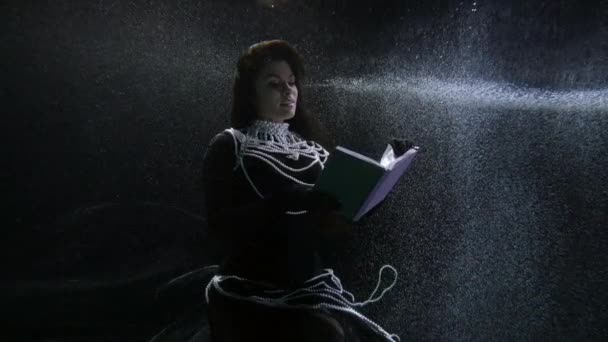 Elegant brunette lady is reading old book underwater, subaquatic shot, magic and fairytale — Stockvideo