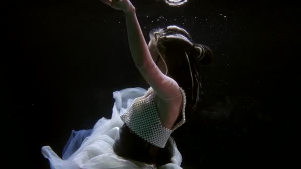 Charming lady is whirling and floating in water of magic lake or river, swimming underwater — Video