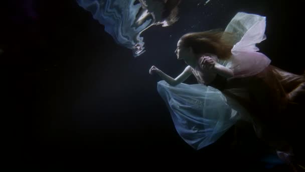 Underwater fairytale, graceful lady in silk dress is swimming under water surface — Video