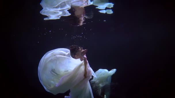 Feminine graceful lady is floating underwater, enigmatic figure of woman is swimming in darkness — Vídeo de stock