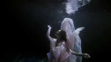 beautiful tender woman is floating in deepness in sea or river, slow motion underwater shot
