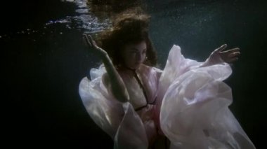 tender woman is swimming inside water of lake or pool, romantic and sensual underwater shot