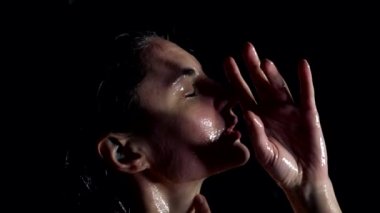 feminine and emotional woman in shower in darkness, sensual portrait